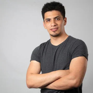 Confident young man in casual grey t-shirt with arms crossed, studio background