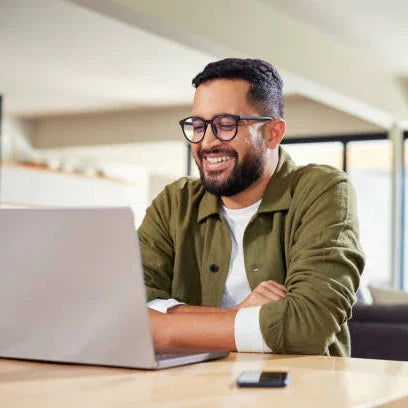 Smiling man using laptop in modern home office, remote work, digital workspace concept