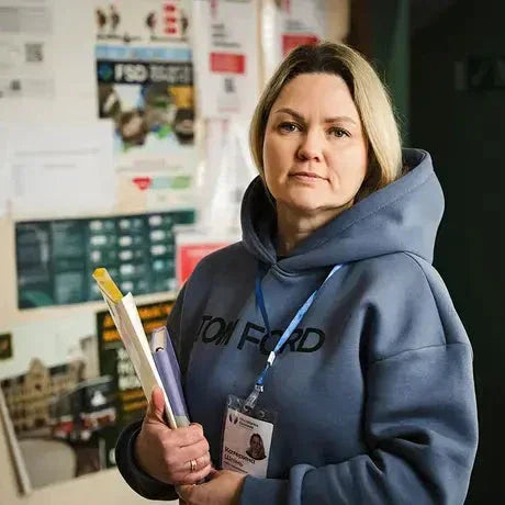 Woman in hoodie holding documents and wearing an ID badge in an office setting