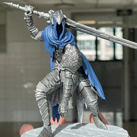 Metallic fantasy warrior figurine with blue cape and sword in an indoor setting