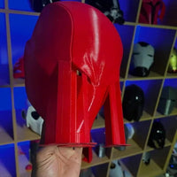 Red high-heeled shoe held in front of a colorful geometric-patterned wall.
