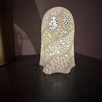 Decorative ceramic lamp with intricate cut-out patterns on a dark surface.