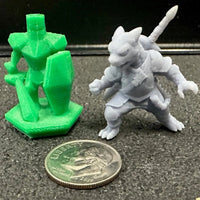 Two 3D-printed figurines, one green and one gray, next to a coin for scale on a dark surface.